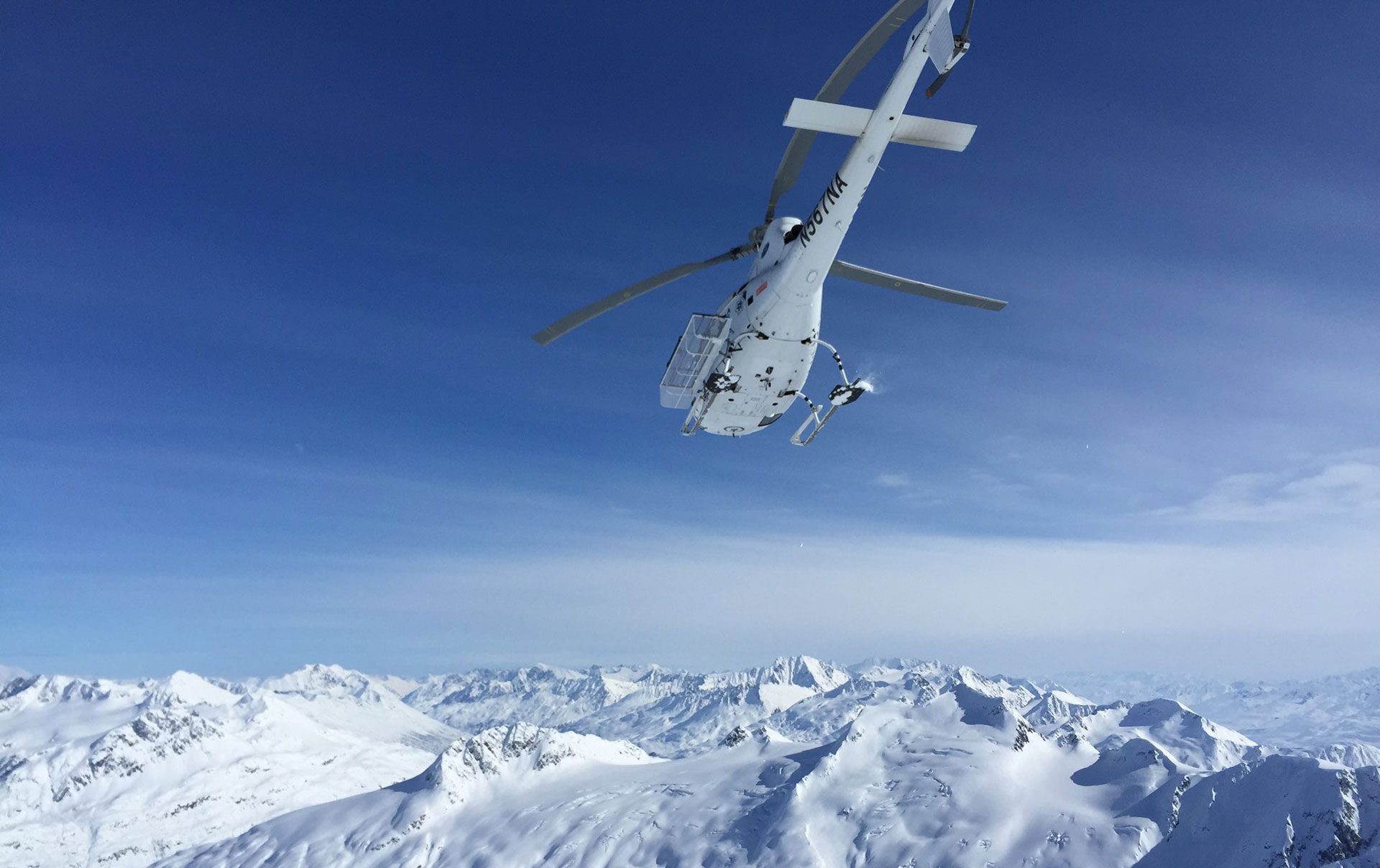White helicopter flying over mountain